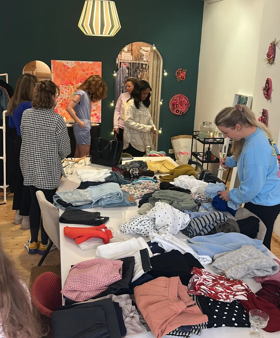 Women browsing clothes on table in boutique.