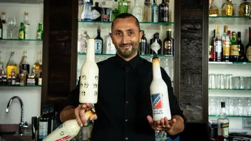 Barkeeper balanciert Flaschen in Barumgebung.