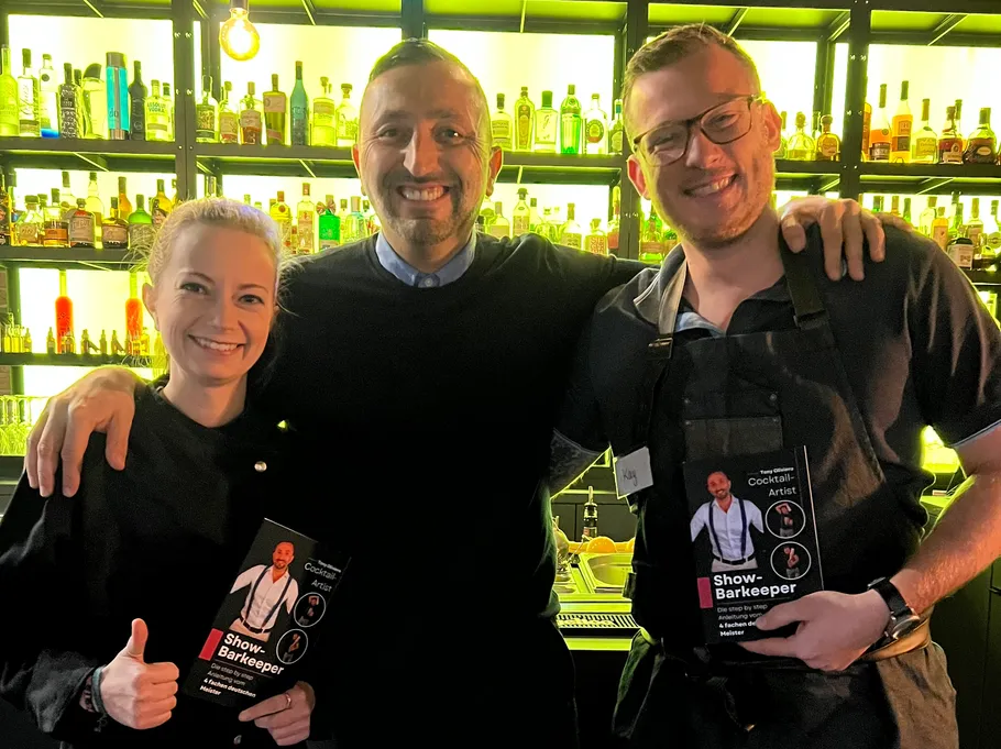Three people smiling in front of a bar.