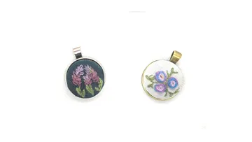 Two embroidered pendants with floral designs.