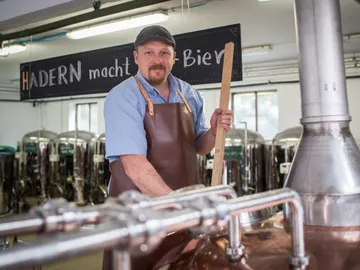 Brewery: Brewer stirs beer in a copper kettle.