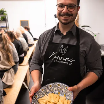 Smiling man holding pasta dish indoors.