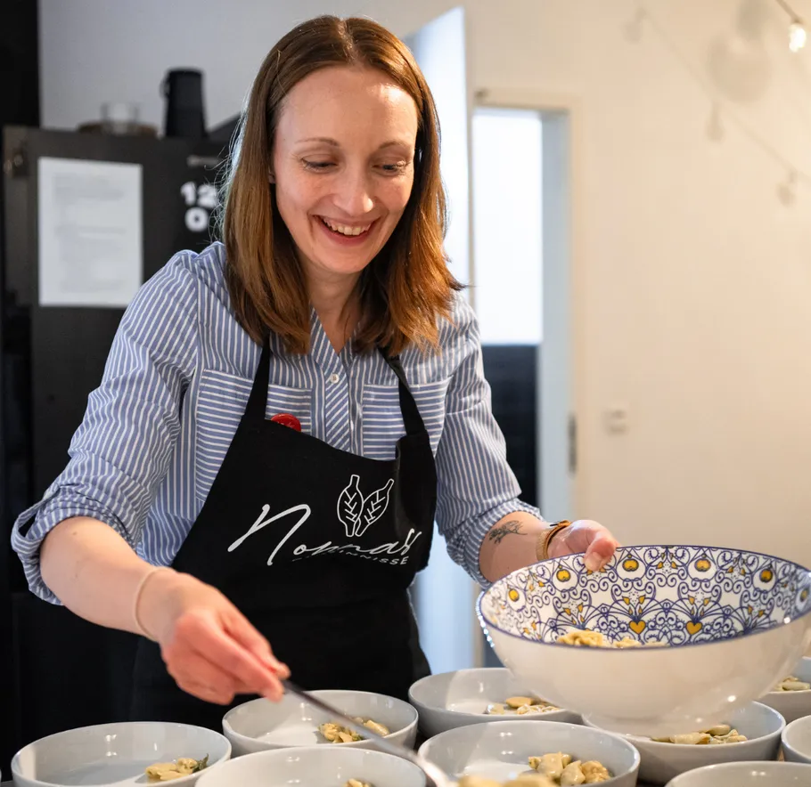 Woman serving food in a kitchen.