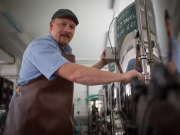 Brauer works on a brewing system in a brewery.