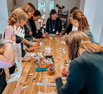 People creating crafts around a wooden table.