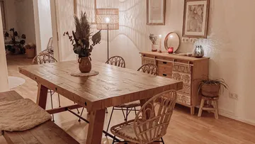 Wooden dining table in cozy, dimly lit room.