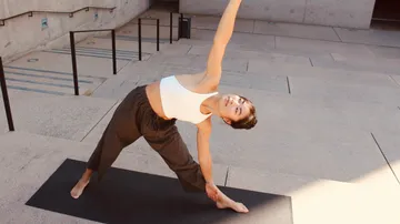 Woman practicing yoga on outdoor mat.