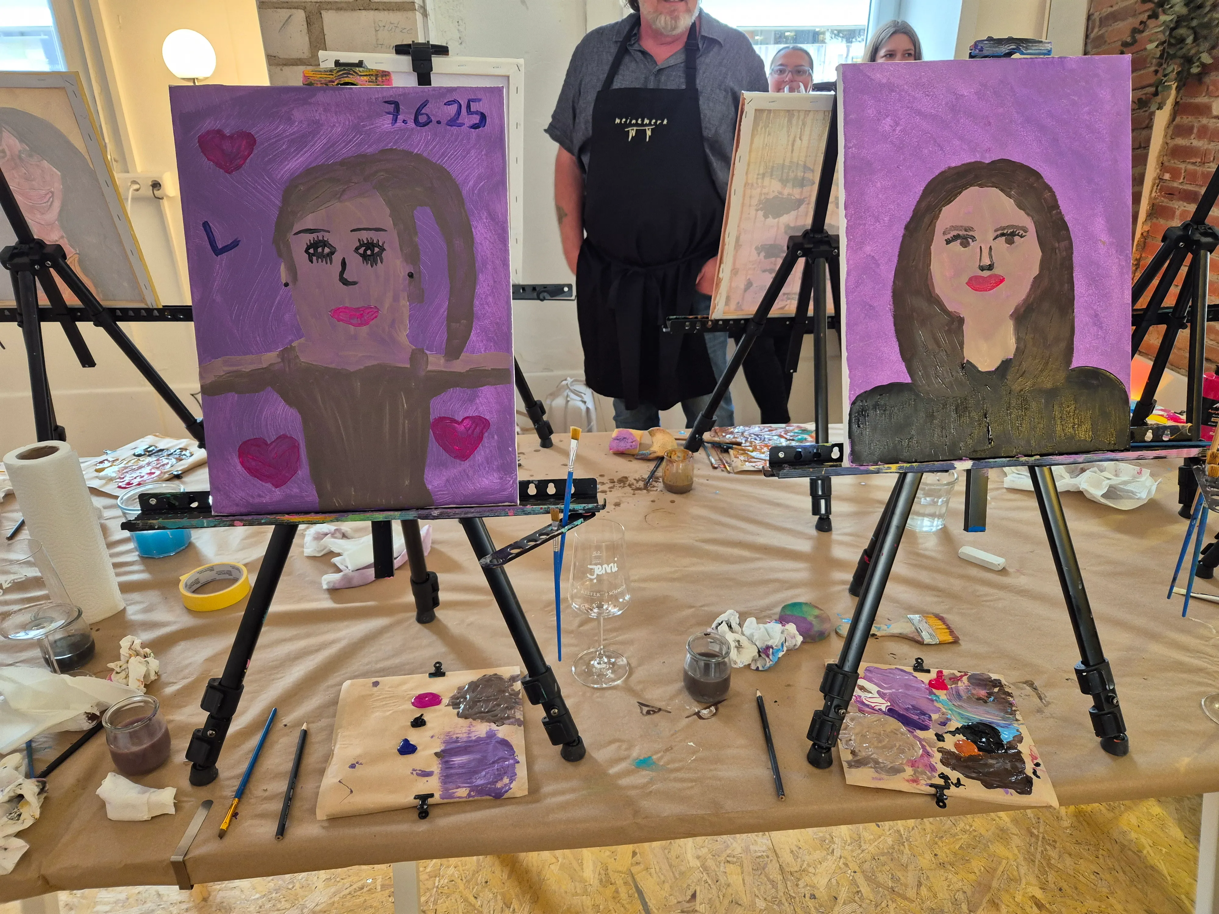 Two portraits on easels, indoor art class.