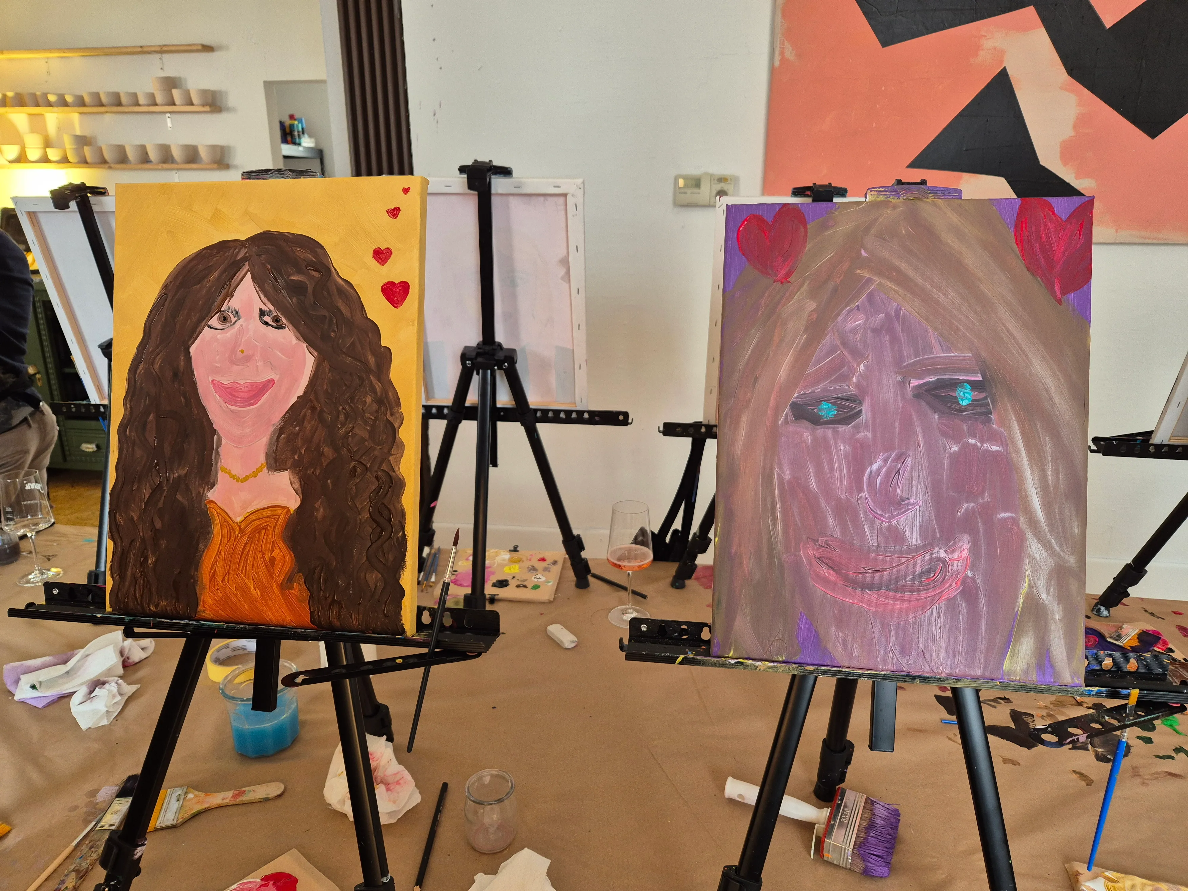 Two portrait paintings on easels in art class.