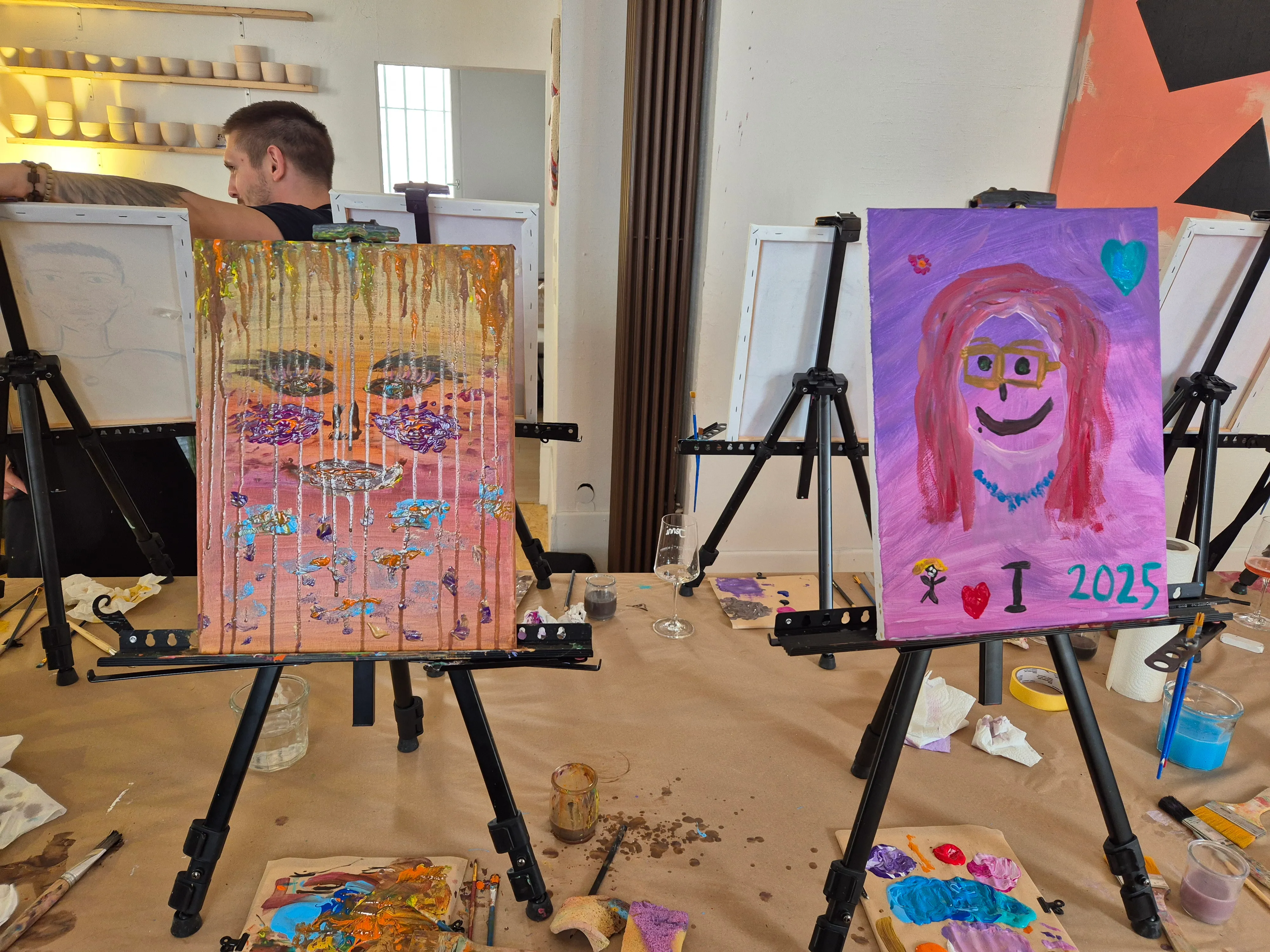 Two colorful paintings on easels in art studio.