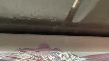 Window with oxidized metal and defect.
