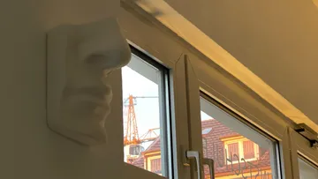 Weiße Nasenskulptur bei offenem Fenster.