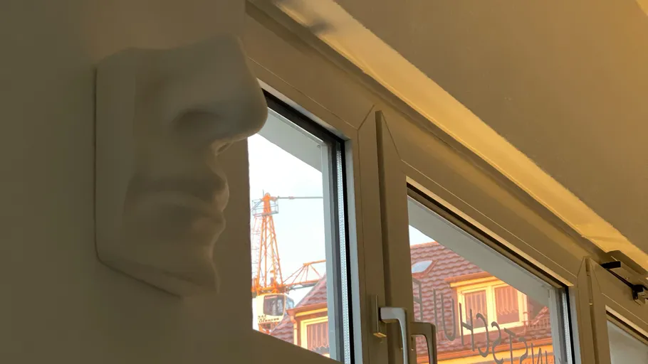Weiße Nasenskulptur bei offenem Fenster.
