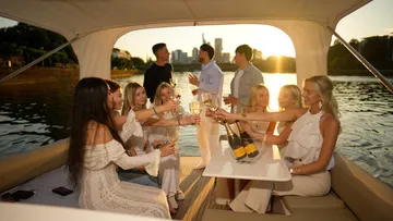 Menschen trinken auf einem Boot bei Sonnenuntergang.