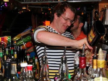 Barkeeper schenkt Getränke aus einer Flasche hinter der Bar.