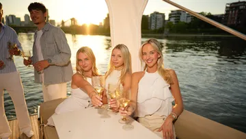 Group enjoying wine on boat at sunset.
