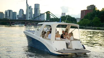 Group on yacht cruising city river.