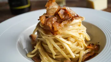Pasta mit Speck auf einem weißen Teller.