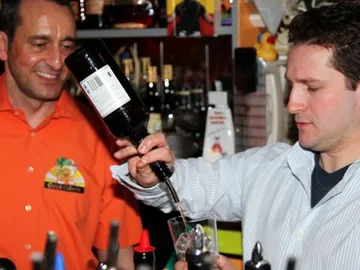 Zwei Männer in einer Bar, einer schenkt Getränk aus.