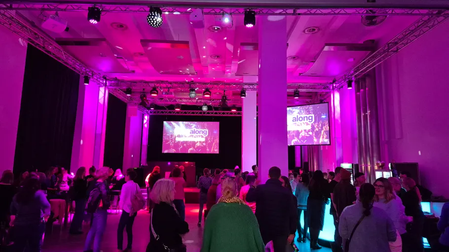 People socializing in a purple-lit event hall.