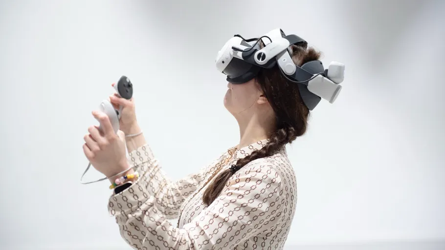 Person wearing VR headset, holding controllers, indoors.