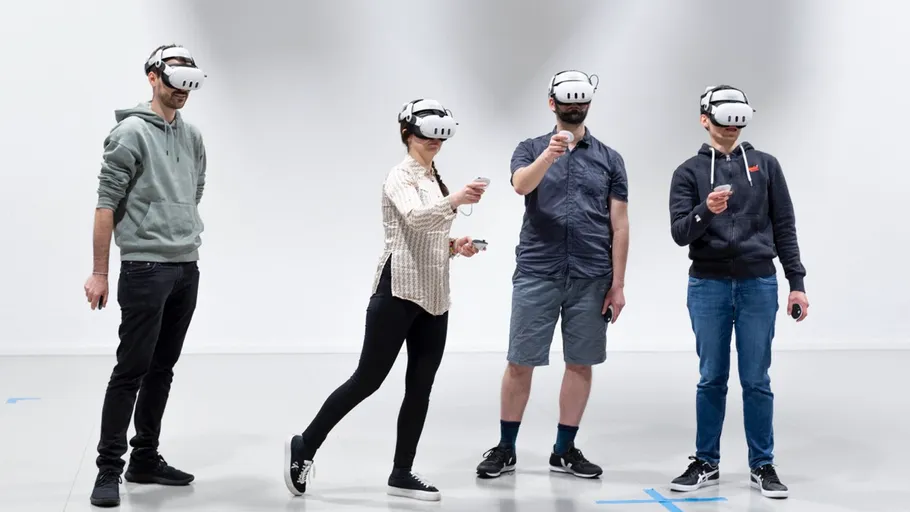 Four people using VR headsets, standing indoors.