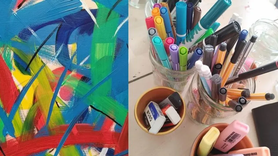Abstract painting and assorted drawing supplies on table.