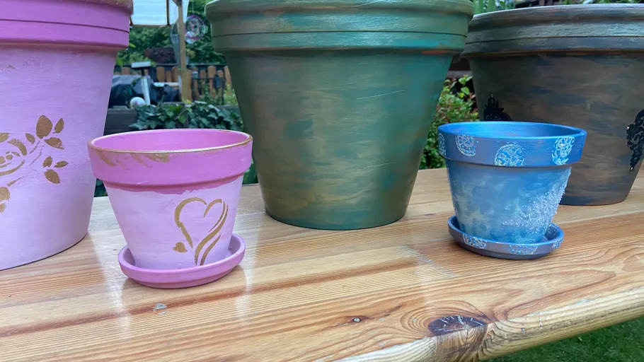 Decorated pots on wooden table outdoors.