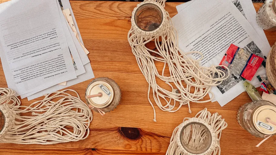 Macrame jars and papers on wooden table.