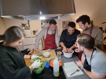 Gruppe kocht zusammen, bereitet frische Zutaten in Küche vor.