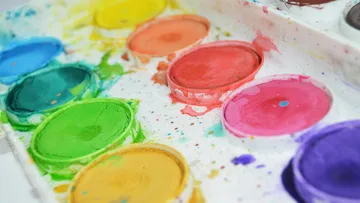 Colorful watercolor paint set with scattered splatters.