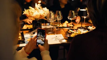 Person fotografiert eleganten Esstisch mit Handy.