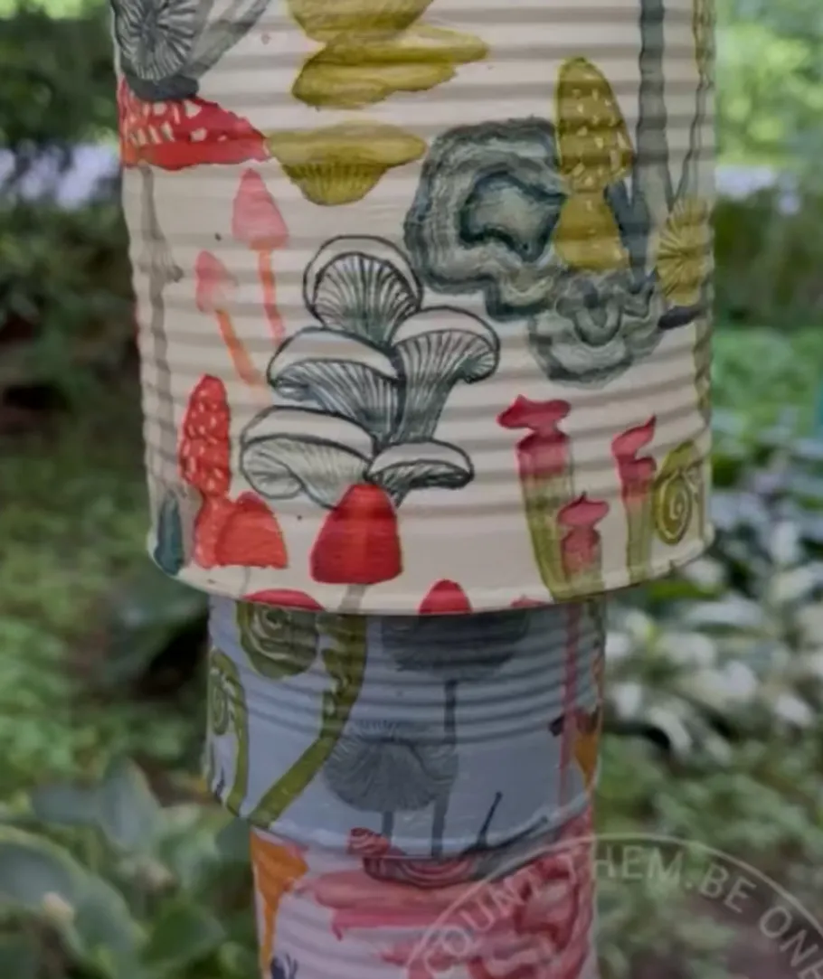 Colorful painted cans stacked in garden.
