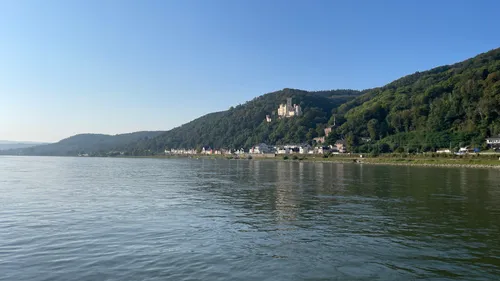 Burg auf Hügel mit Blick auf Fluss und Dorf.