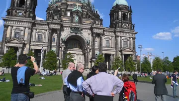 Tourists photographing Berlin Cathedral on a sunny day.