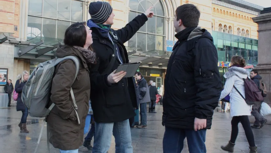 Three people discussing outside a train station.
