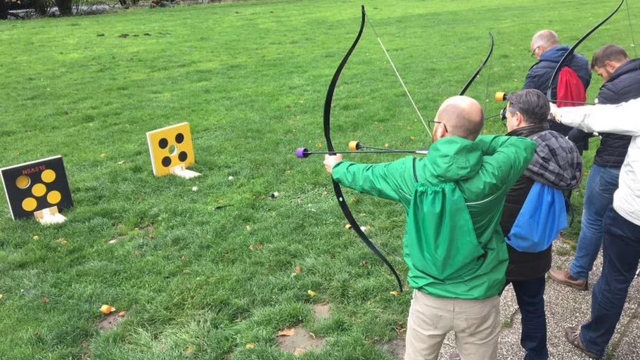 People practicing archery on grassy field.