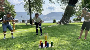 Drei Personen spielen ein Seilspiel auf Rasen.