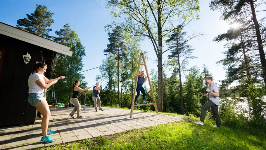 People swinging outdoors, surrounded by trees.