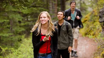 Three people hiking on a forest trail.