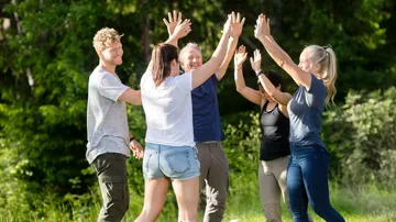 Group of people giving high fives outdoors.