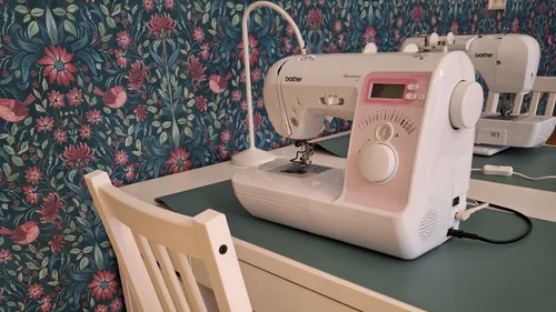 Sewing machine on table, floral wallpaper background.