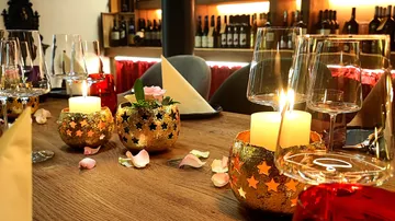 Table with candles, petals, and wine glasses.