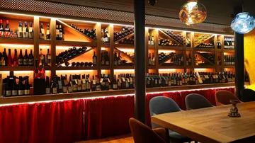 Wine bottles displayed on wooden shelves with lighting.