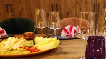 Cheese plate on wooden table with glasses.