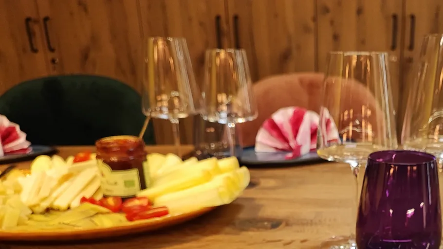 Cheese plate on wooden table with glasses.
