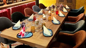 Elegant dining table with colorful chairs, set for dinner.