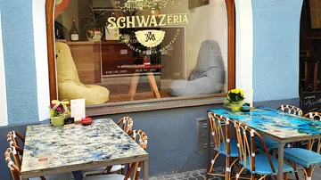 Outdoor cafe tables beside a window display.