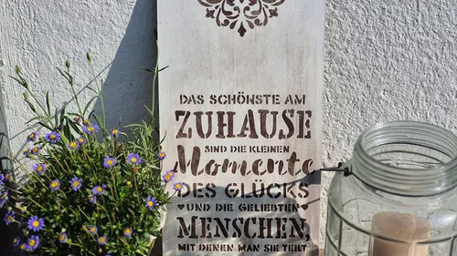 Decorative sign with German text next to flowers.