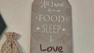 Dekoschild mit Text und Herzmustern.